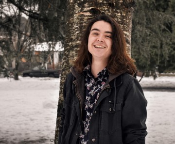 Artist Joshua Ralph smiling, standing in front of a tree.