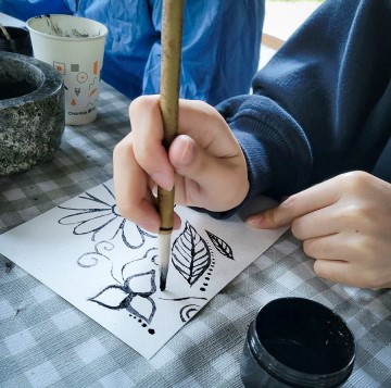 A person drawing on paper with a pencil, part of Natural Ink Making with Invasive Species workshop.