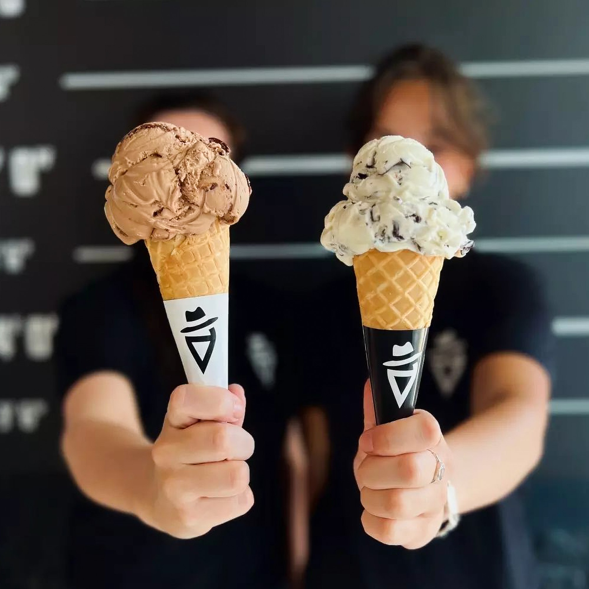  The scene also includes two girls holding gelatos on waffle cones. The tags associated with the image are ice cream, dairy, food, dessert, person, ice cream cone, frozen dessert, gelato, snack, holding, and indoor.
