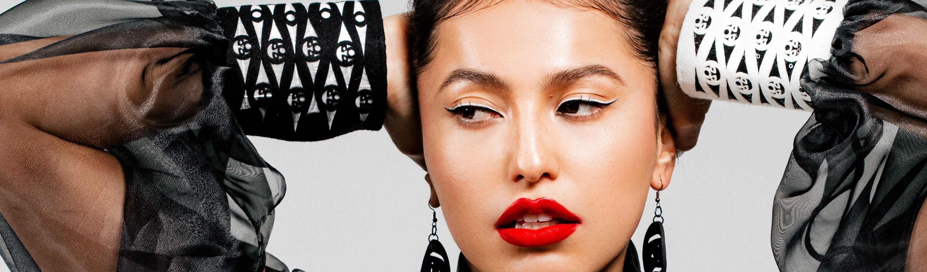 The image features a person with red lipstick, identified as a woman, posing for the Pam Baker exhibition. The focus is on the human face, showcasing fashion and art elements.