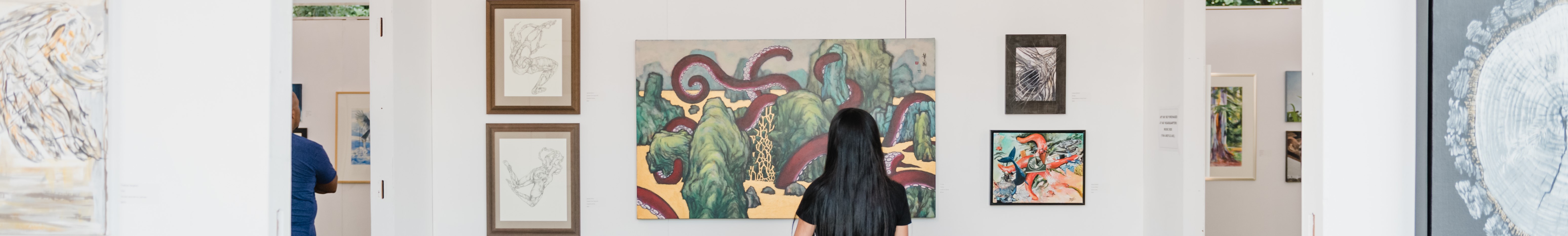 A woman admiring a painting in an art gallery, captivated by the colors and brushstrokes.