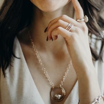 The image features a woman wearing a gold necklace as a fashion accessory. The woman is also wearing other jewelry pieces like earrings and body jewelry. The setting appears to be indoors. The jewelry is from Joanna Lovett Sterling.