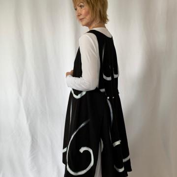 The image shows a person wearing a black dress from the Art to Wear clothing brand. The person is indoors and the dress features a pattern. The individual appears to be a young woman.