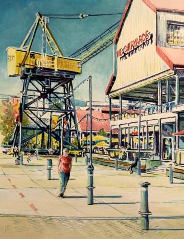 The image depicts a person walking on a sidewalk at The Shipyards. The setting includes outdoor elements such as the sky, street, and buildings. The artwork is by Michael Gordon Brouillet.