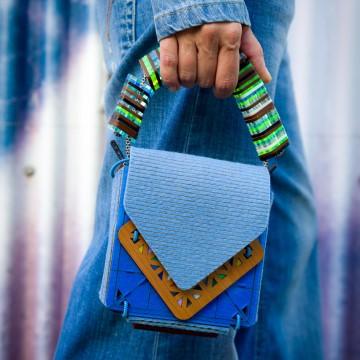  It is related to Studio Jazbi fashion accessories and features a blue bag. The person is wearing a striped clothing item