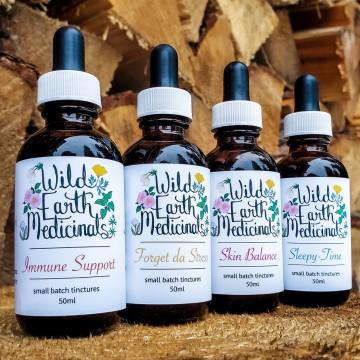 The image shows a group of bottles labeled with various phrases related to medicinal products, such as "Immune Support" and "Skin Balance". The bottles are small batch tinctures in 50ml size from Wild Earth Medicinals.