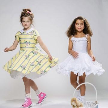 The image features two girls wearing dresses. The setting appears to be indoors. The clothing worn by the girls is from the Rarity clothing brand. The girls are wearing sneakers and the dresses have ruffle details.