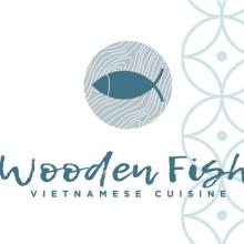 The image is a logo for a Vietnamese cuisine restaurant named "Wooden Fish." The design features a wooden fish graphic along with the text "VIETNAMESE CUISINE" in a circular layout. The logo is for the Wooden Fish restaurant.