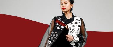 The image features a model wearing a black and white dress against a white background. The person is likely part of a fashion show celebrating Indigenous fashion by Himikalas Pamela Baker.